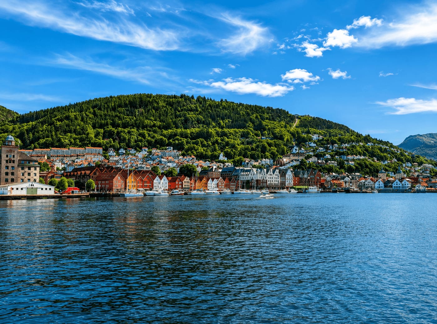 The wooden wharf houses of Bryggen along Bergen's harbour, with the forested slope of Fløyen rising behind them